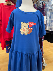 A toddler girl's tiered blue dress displayed on a mannequin in a clothing store. The dress features a graphic of a teddy bear holding a football and a red flag that says 'Buffalo' with the number 17.